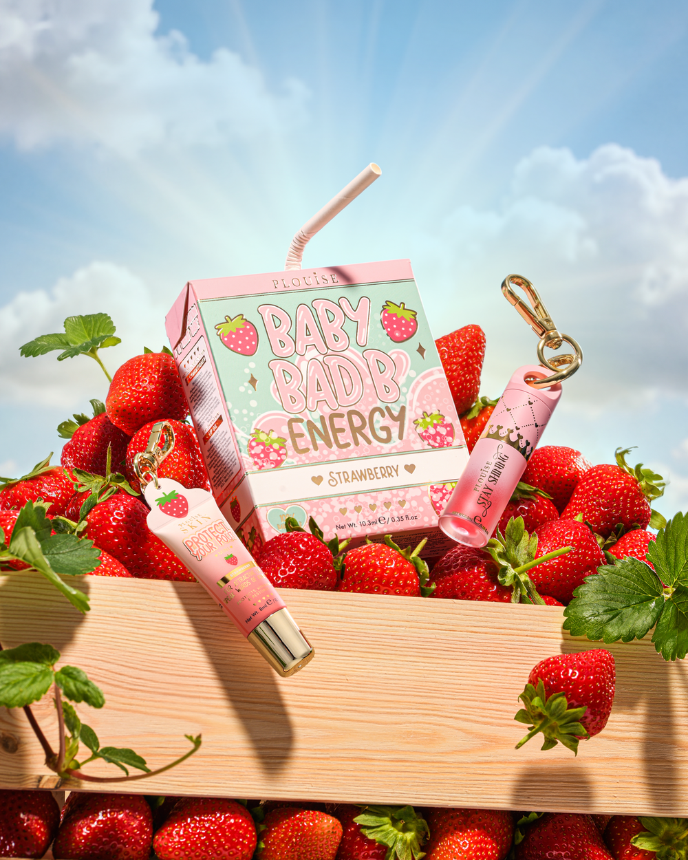 P.Louise Strawberry Baby Bad B Mini Lip Oil and Mini Lip Conditioner on a table surrounded by strawberries