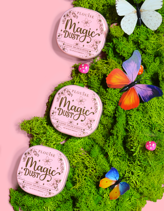 Three P.Louise Magic Dust Loose Highlighter pans displayed on a bed of moss, with butterflies and decorative accents.