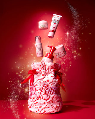 Pink Christmas P.Louise bag with red festive bows and a festive design on it with body care products coming out the top on a red background