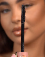 Gros plan d'une baguette de mascara imperméable P.Louise Tearproof tenue devant un visage flou