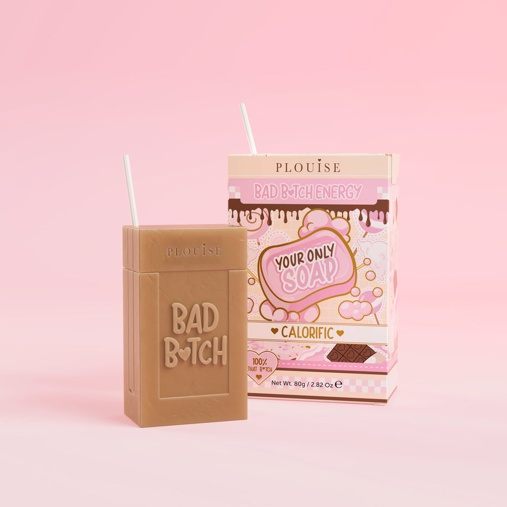 Een bruin stuk zeep met 'Bad Bitch' erop gegraveerd, vergezeld van een kleurrijke sapdoos met het label 'Calorific' erop, gepresenteerd op een roze achtergrond.