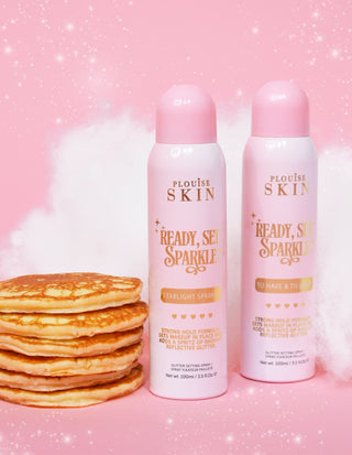 Two aerosol cans of P. Louise Ready Set Sparkle Glitter Setting Spray with a stack of pancakes and a pink background with sparkles