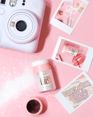 A container of P.Louise Say It With Chest Loose Body Glitter in Golden Era shade, with the cap removed, displayed on a surface with a reflective and sparkling appearance.