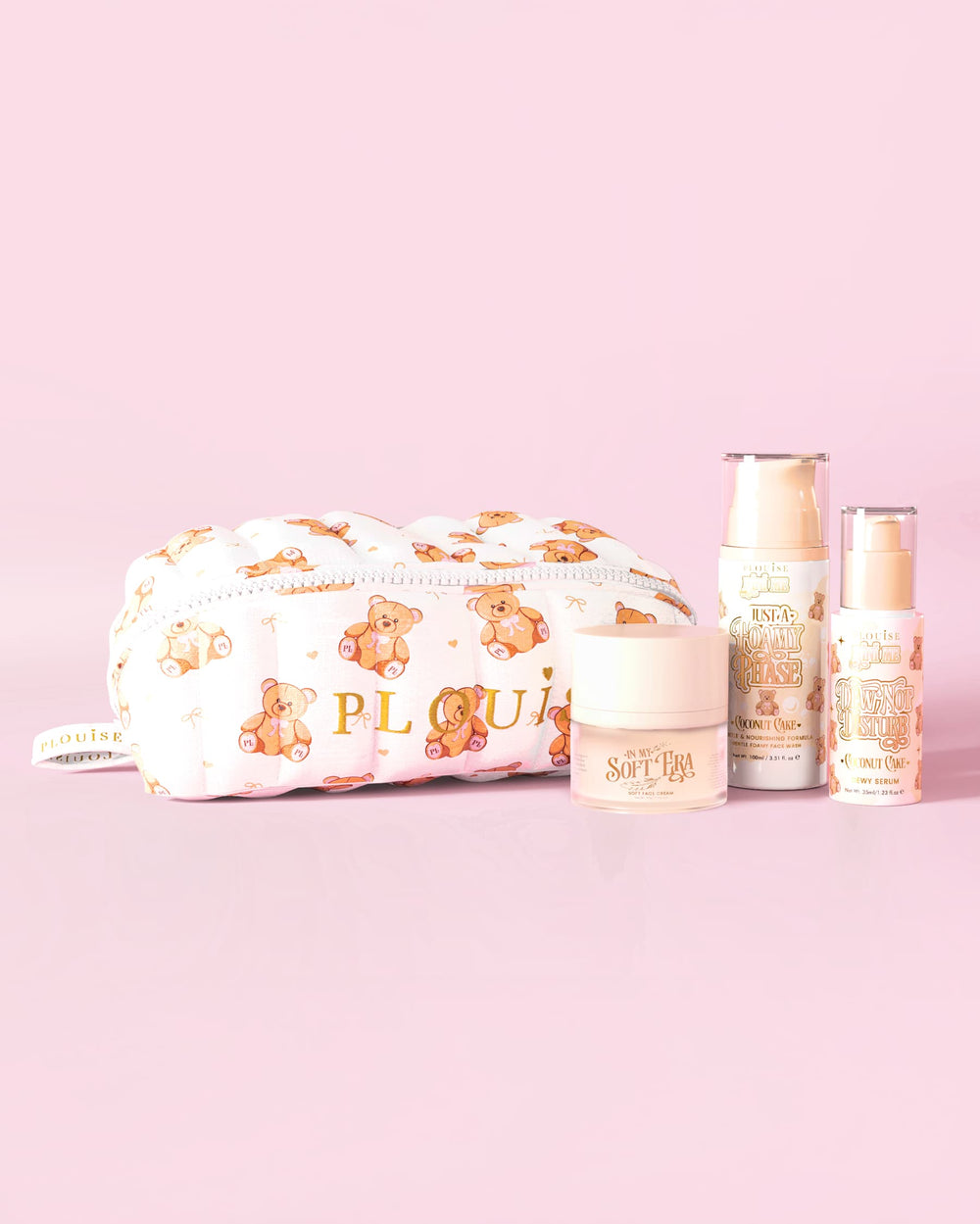 Een afbeelding van de P.Louise Softest Touch Skincare Starter Kit met een grote print teddybeer huidverzorgings- en make-uptas en 3 huidverzorgingsproducten tegen een roze achtergrond