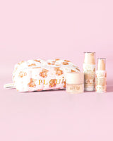 Een afbeelding van de P.Louise Softest Touch Skincare Starter Kit met een grote print teddybeer huidverzorgings- en make-uptas en 3 huidverzorgingsproducten tegen een roze achtergrond